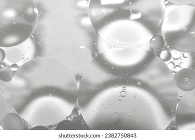 Drops of clear oil on the surface of cosmetic water or serum.