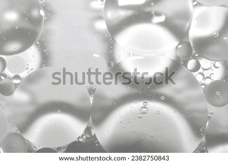 Drops of clear oil on the surface of cosmetic water or serum.