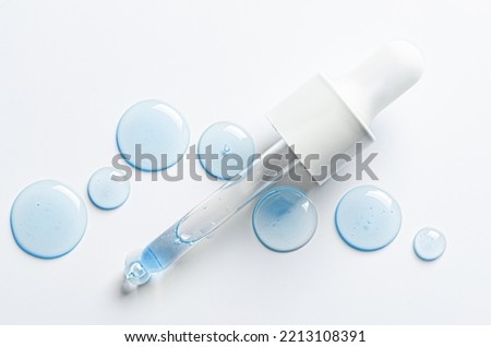 Drops of cosmetic serum and a pipette. A skin care product. White background. Copy space.