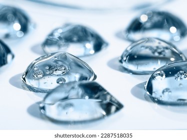 Drops of hyaluronic acid with bubbles front view, macro. Cosmetic texture on a blue background, liquid, transparent product. - Shutterstock ID 2287518035