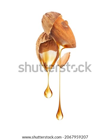 Drops of oil dripping from crushed almonds close-up on a white background