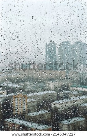 Drops on glass on rainy cloudy day evoke melancholy and sadness. View of city from the window. Selective focus