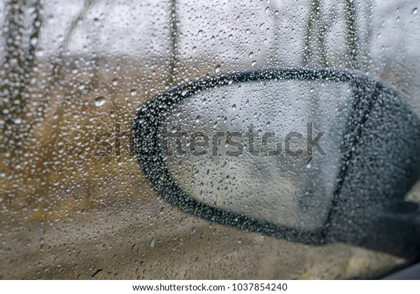 Drops on the glass window of car. Dramatic blurry\
background of street rain