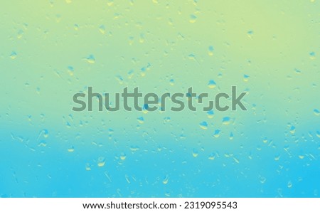 Drops on a glass with a yellow-blue gradient and sunlight.