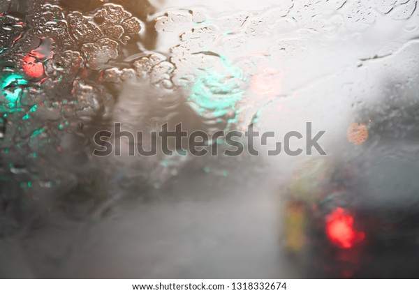 Drops Of Rain\
Drizzle on the glass windshield in the evening. street in the heavy\
rain. Bokeh Tail light and Traffic lights. Please drive  car\
carefully, slippery road. soft\
focus.