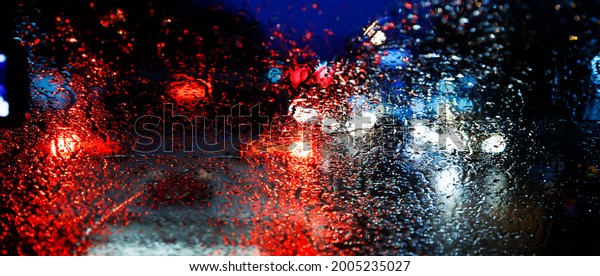 Drops Of Rain\
Drizzle on the glass windshield in the evening. street in the heavy\
rain. Bokeh Tail light. soft Focus. Please drive carefully,\
slippery road. soft\
focus.