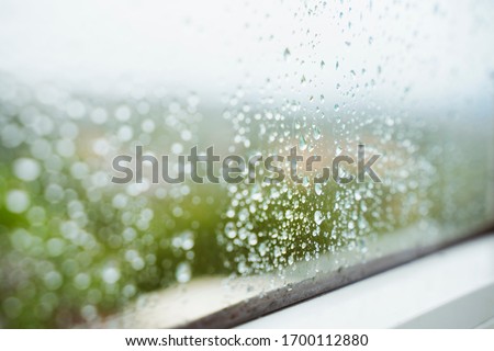 Drops of rain horizontal background. Winter seasonal time. Humidity and rainy weather inside home. Water condensation on window. Detail of wet drops of rain stick to a clean window at home.