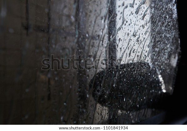 Drops\
of rain on car window pane, wet window of the\
car