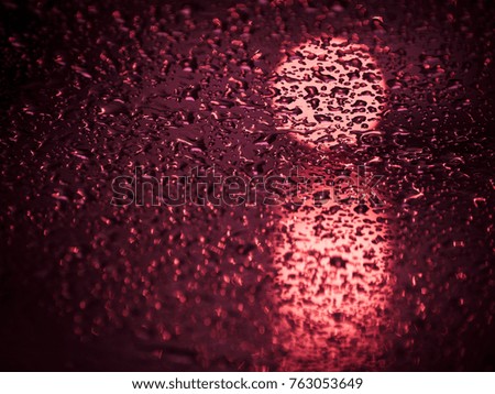 Drops of rain on the glass with lights on the background