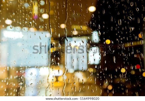 Drops of\
rain on window with abstract bokeh\
background