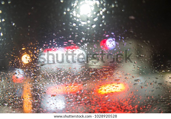 Drops of rain on the\
window of the car, the lights of the night city in blurring. Rain\
drops on car glass