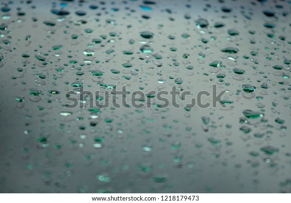 Drops of rain on the window glass. Shallow DOF.\
Window after rain. Light green water background with water\
drops.Incline camera\
angle.