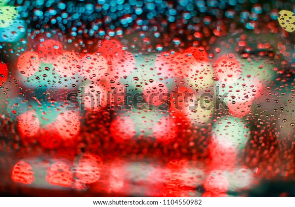 Drops\
Of Rain Water In Night Or Evening Street Lights On Red Glass\
Background. Street Bokeh Boke Lights Out Of\
Focus.