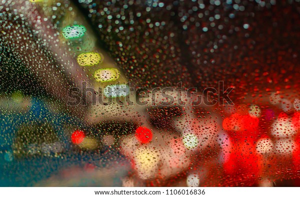 Drops
Of Rain Water In Night Or Evening Street Lights On Red Glass
Background. Street Bokeh Boke Lights Out Of
Focus.