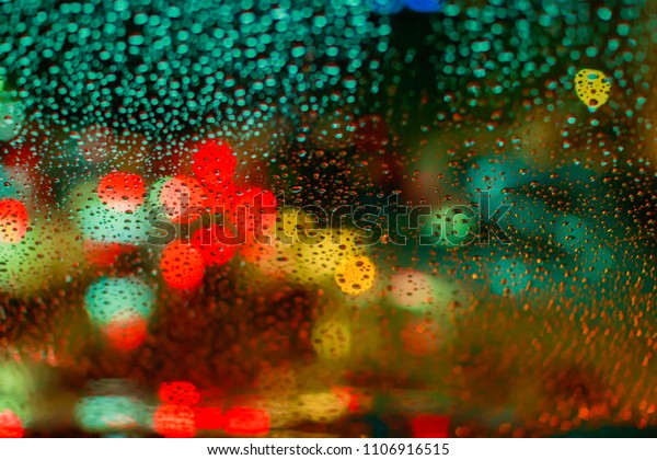Drops\
Of Rain Water In Night Or Evening Street Lights On Red Glass\
Background. Street Bokeh Boke Lights Out Of\
Focus.