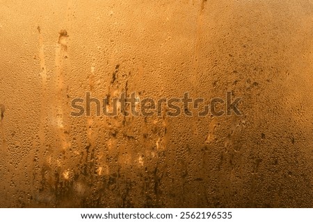 drops are running down the window. wet glass brown background