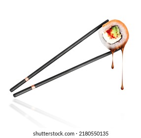 Drops of soy sauce drip from sushi roll with salmon sandwiched between sticks close-up - Powered by Shutterstock