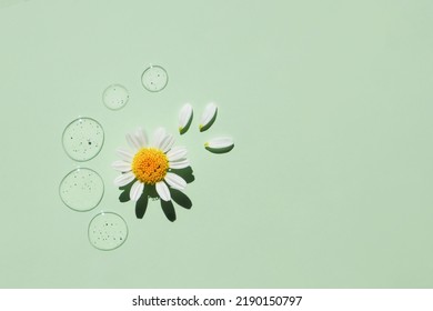 Drops of transparent cosmetic gel with natural chamomile on a green background. Top view, cosmetic product. - Shutterstock ID 2190150797