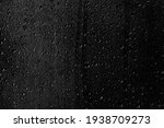 Drops of water flow down the surface of the clear glass on a black background. Texture for creativity.