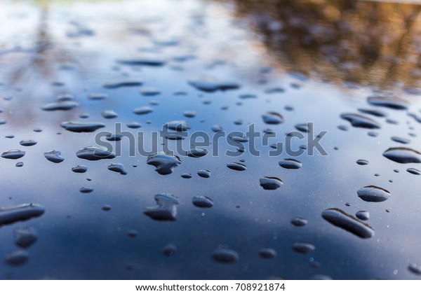 Drops of water on\
black car paint. closeup on a spot on the Roof. transparent water\
drops on auto paint.