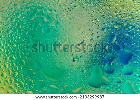 Drops of water on a blurred green-blue glass background.