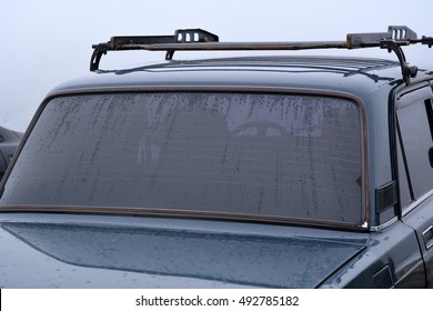 Drops Of Water On The Tinted Back Window Of The Car. The Car In The Fog