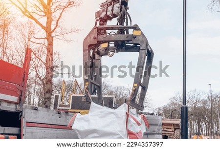 Dropside flatbed HIAB crane lorry with brick grab attachment deliver materials on construction site and offloading them