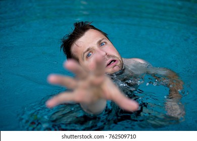 Drowning caucasian man in swimming pool asking for help. He stretching his hands in fear. Emotional stress in dangerous situation. Do not know how to swim.