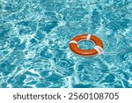 Drowning concept. No swimming. Rescue swimming ring in water. Safety water equipment. Lifebelt on sea or pool. Orange inflatable ring floating in blue water. Rescue at pool.