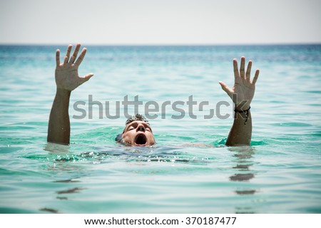 Drowning man in sea asking for help with raised arms.