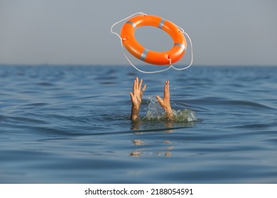 Drowning woman with raised hands getting lifebelt in sea