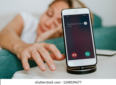 Drowsy Woman Reaching For Her Phone To Turn Off The Alarm