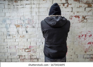 A drug addict in the hood, experiencing a drug addiction crisis, against a brick wall. Lifestyle, addiction concept.