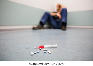 Drug Addicted Person With Syringe And Pills On The Floor