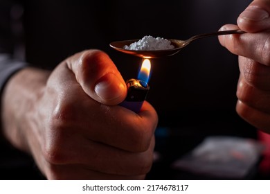 Drug addicts in the dark room. Addict preparing drugs with a spoon and lighter. White powder and a syringe. Drug concept. International drug abuse day.