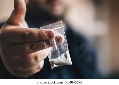 Drug dealer offers cocaine dose or another drugs in plastic bag, drug addiction on party concept, selective focus, toned