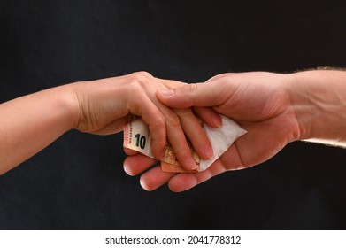 Drug Dealer Passes A Dose To A Merchant, Sachets Of Powder On A Black Background.new