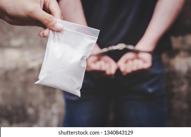 Drug dealers was under arrested and locked the arms bad guy behind his back at the wall by using handcuffs. It has evidence, policeman shows cocaine, heroine or narcotic contains in the plastic bag
