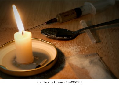 Drug Syringe And Cooked Heroin On Spoon. Cocaine In The Bag, Scattered. Candle Burns. Evening.