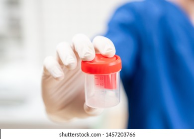 Drug test. Doctor in blue uniform and medical gloves holding a container for semen analysis. Donor sperm for artificial insemination, infertility treatment, planning of children