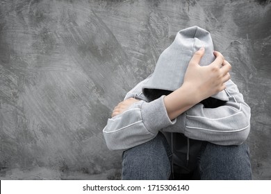 Drugs Addiction And Withdrawal Symptoms Concept. Depressed And Hopeless Teenage Girl Sitting Alone After Using Drugs Or Drunk Alcohol Over Grunge Concrete Wall. International Day Against Drug Abuse.