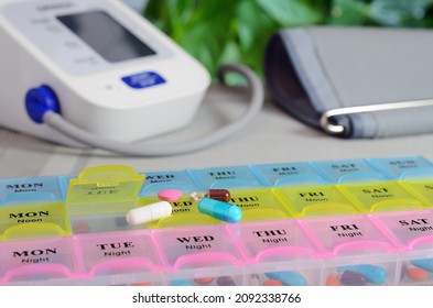 Medikamente aus einem farbigen Tablettenbehältnis und einem digitalen elektronischen Tonometer. Konzept der Gesundheitsversorgung.