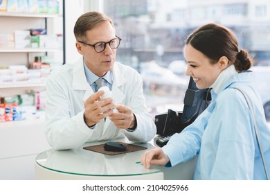 Drugstore pharmacy consultation. Caucasian male pharmacist druggist advising selling medicines, pills, drugs, painkillers, vitamins to a female customer client, buyer in drugstore