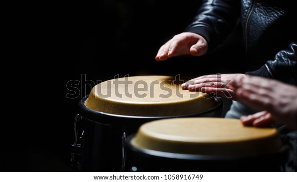 Drum. Hands of a musician\
playing on bongs. The musician plays the bongo. Close up of\
musician hand playing bongos drums. Afro-Cuba, rum, drummer,\
fingers, hand, hit.