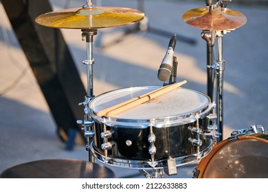 Drum kit at outdoor rock party, drumsticks on tom-tom drum. Drum set with drum sticks ready for playing music at summer outdoor rock performance, close up
