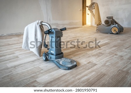 Drum sander and floor edger machine on hardwood flooring during parquet restoration