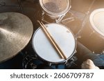 Drum set with drumsticks on snare drum in rehearsal studio, music production or musical education, sound recording content