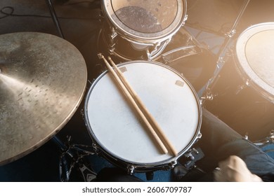 Drum set with drumsticks on snare drum in rehearsal studio, music production or musical education, sound recording content