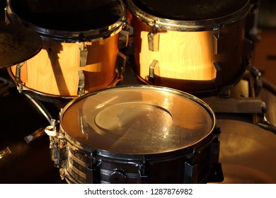 Drum set illuminated by the rays of the setting sun in a music studio. Closeup.