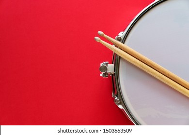 Drum and drum stick on red table background, top view, music concept